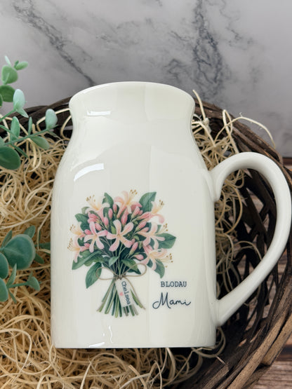 Personalised June birth flower jug in Welsh featuring a watercolour honeysuckle design, custom name and personalised mini message tag.