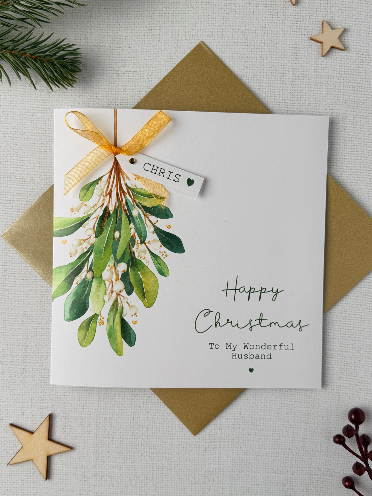 Personalised mistletoe Christmas card with watercolour mistletoe design, gold ribbon bow and raised name tag, perfect for a husband, wife, boyfriend, girlfriend or loved one.