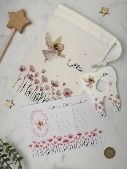 A styled flat-lay of a personalized fairy-themed letter set on a white marble background, including a drawstring pouch, a tooth loss chart and a coin holder.