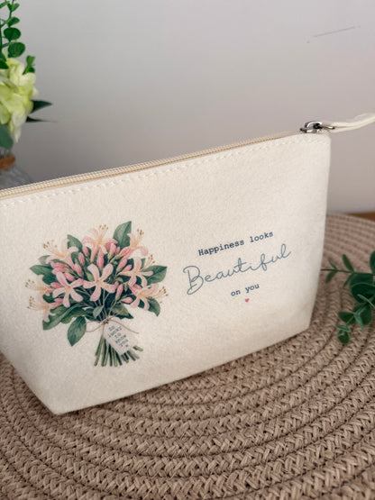 Cream personalised floral accessory bag, ideal for storing makeup, jewellery and everyday essentials with the wording Happiness looks beautiful on you.