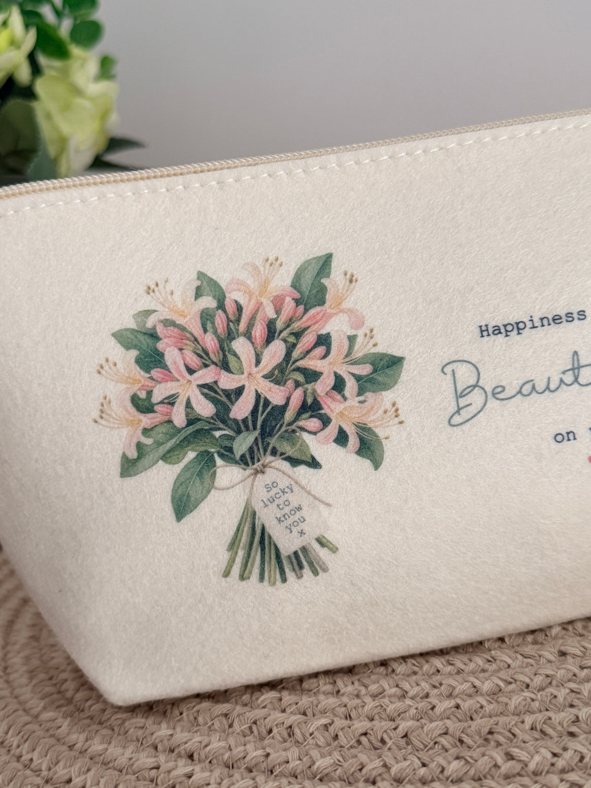 Close-up of the pink floral honeysuckles design and uplifting wording on a personalised cream felt makeup bag.