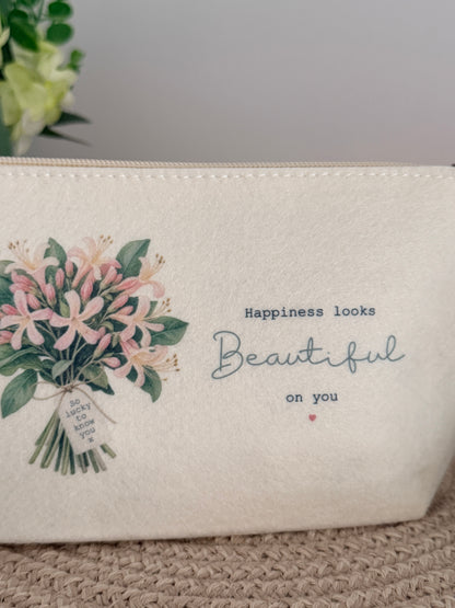 Personalised floral felt makeup bag styled on a neutral woven surface, a thoughtful gift for her.