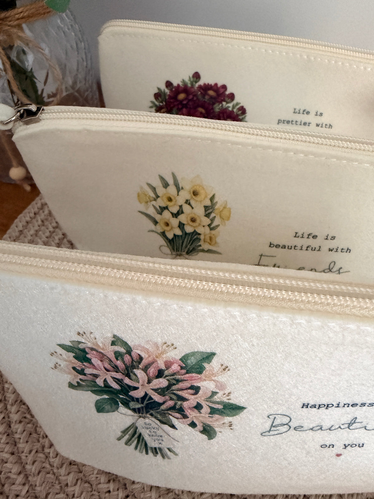 Personalised cream felt bags displaying the floral bouquet design, shown together to illustrate the available styles.