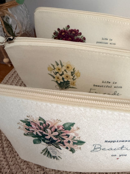 Personalised cream felt bags displaying the floral bouquet design, shown together to illustrate the available styles.